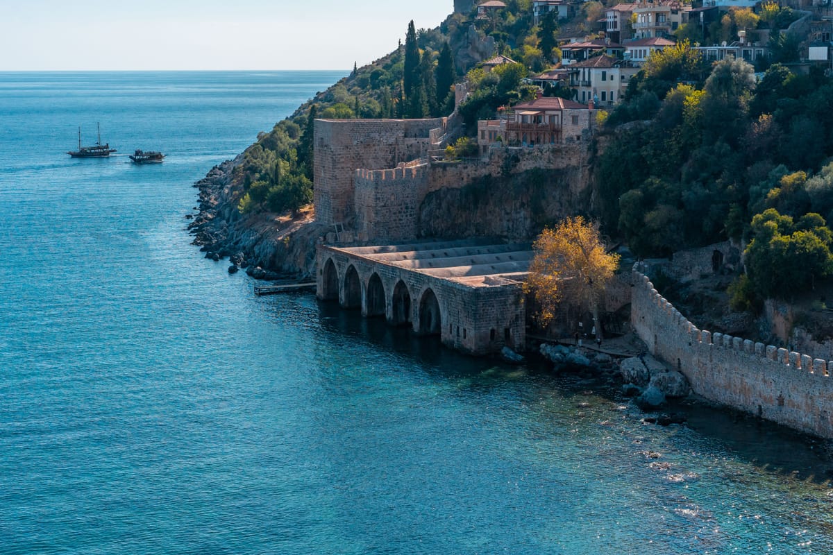 The Ottoman shipyard and the walls of Alanya castle standing over the Mediterranean on the Antalya coast, two gulets at anchor offshore