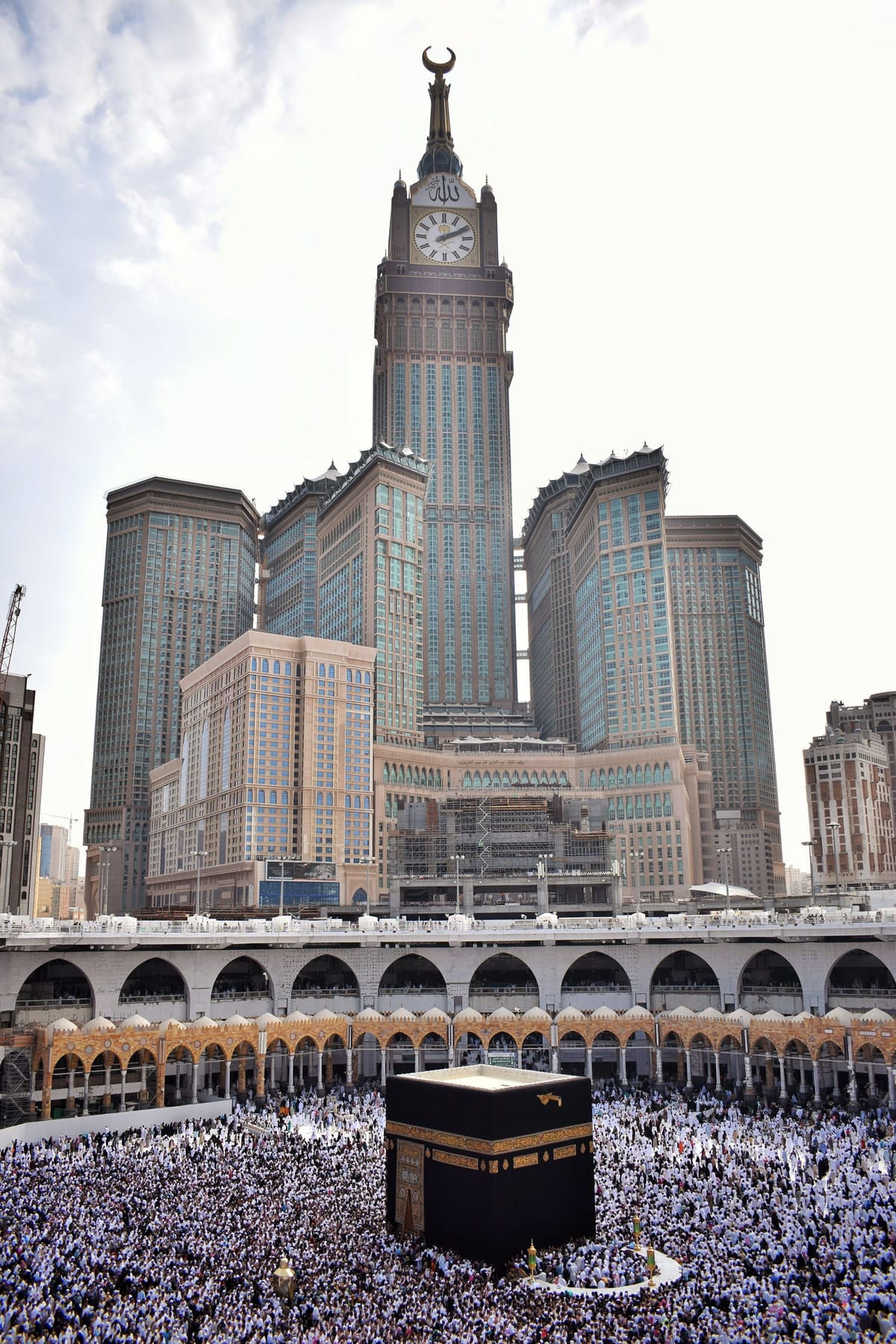 The hotel towers of Makkah standing directly over Masjid al-Haram, the Kaaba and the courtyard filled with pilgrims below them